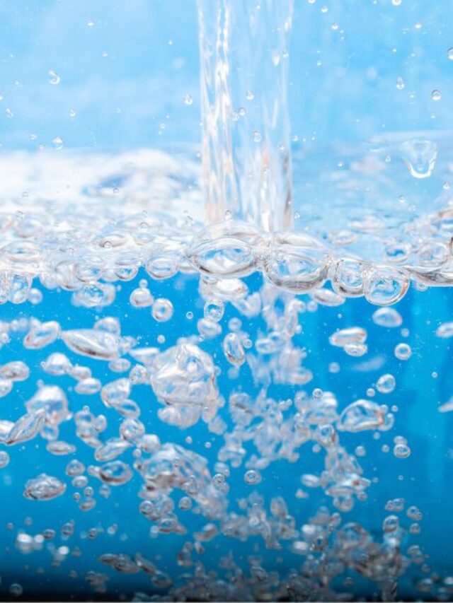 Recipiente de vidro transparente sendo enchido com água pura, com bolhas borbulhando, transmitindo a sensação de frescor e pureza.