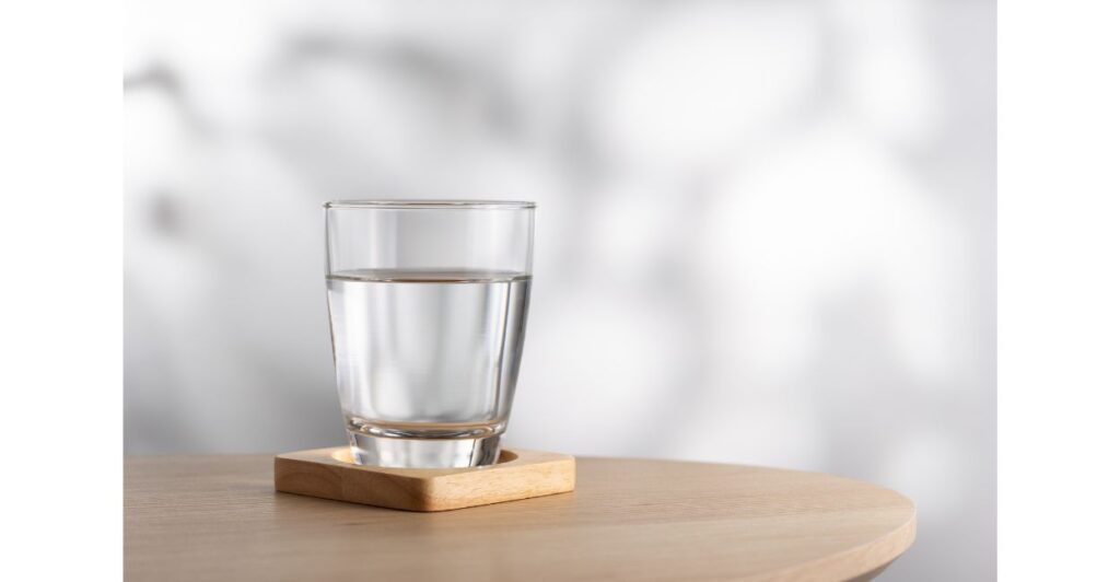 Copo de água limpa sobre uma mesa, representando água filtrada e alcalina.