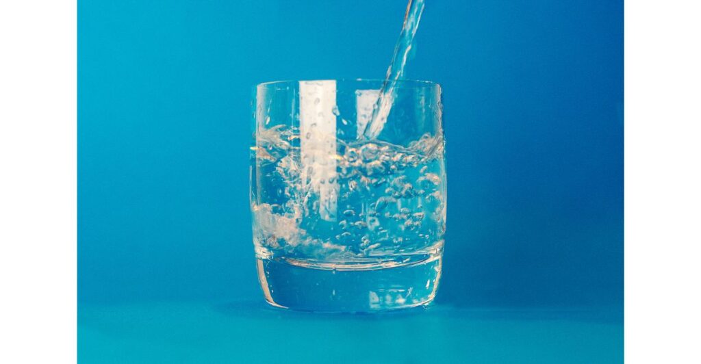 Copo sendo enchido com água pura em um fundo azul.