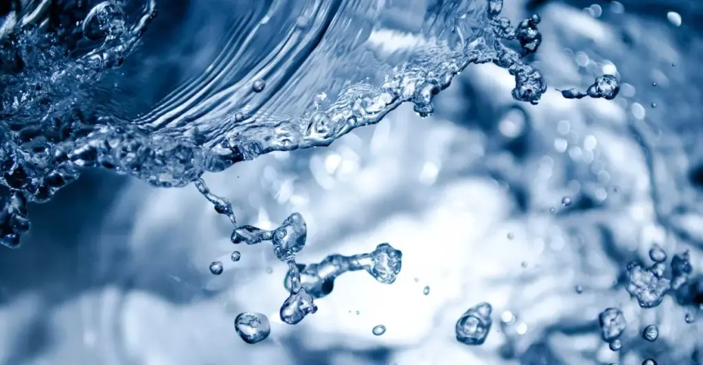 Água alcalina ionizada se movimentando dentro de um recipiente transparente, com bolhas e reflexos de luz destacando sua pureza e vitalidade.